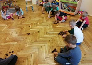 dzieci bawią się kasztanami układając kształty